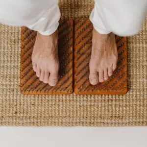 High angle of crop anonymous barefoot male standing on sharp metal nails during yoga session